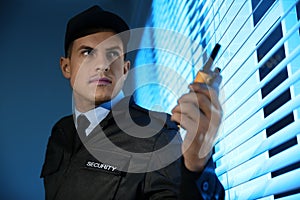 Professional security guard with portable radio set near window in room