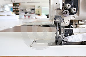 Professional sewing machine overlock in the workshop. Equipment for edging, hemming or stitching clothes in a tailor shop.