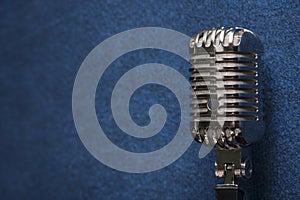 A professional shiny modern dynamic studio vocal microphone on a stylish dark blue grunge vintage background texture