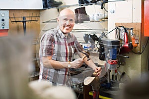 Professional shoemaker heeling footwear on machine