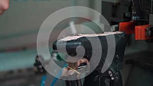 Professional shoemaker working with automatic machinery at shoe factory