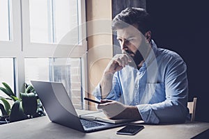 Professional sitting in office in front of laptop. Home-based student getting distant education. Serious man working on desktop