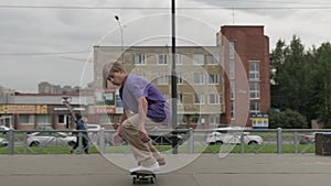 Professional skater teenager is engaged in extreme sports in skatepark doing tricks, skateboarder young blond boy rides