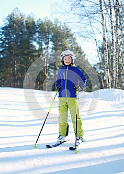 Professional skier child boy in sportswear helmet on ski winter, snowy day on hill mountain over forest