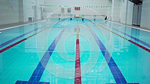 Professional skill male swimmer in indoor pool swimming across track. Healthy lifestyle. Sports and recreation.