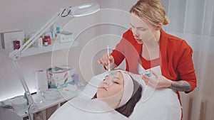 professional skincare in cosmetology clinic, female aesthetician applying clay mask on woman face