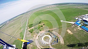 Professional skydiver fly in sky above road. Sunny. Landing on green field