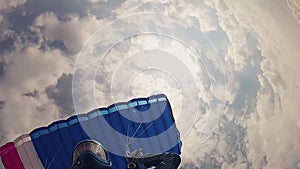 Professional skydiver in helmet parachuting in cloudy sky. Height. Sport. Speed.