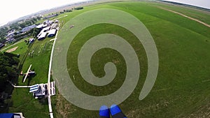 Professional skydiver landing on green field. Grass. Sunny day. Extreme sport