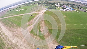 Professional skydiver landing on green field. Summer. Landscape. Sunny day