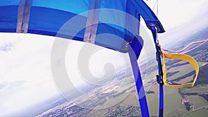 Professional skydiver on parachute fly above green field. Height. Extreme sport