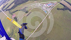 Professional skydiver on parachute fly over green field, forest. Extreme sport