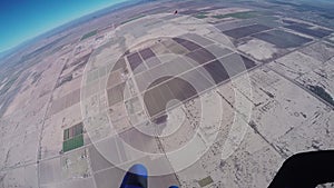 Professional skydiver parachuting in blue sky above sandy Arizona. Landscape