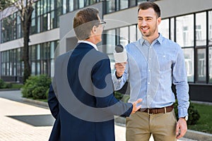 professional smiling journalist interviewing successful mature businessman