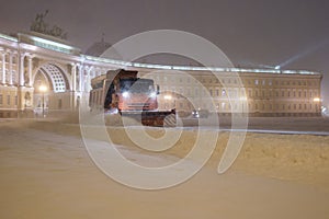 Professional snow removal equipment clearing place square at night after intense snowfall in city