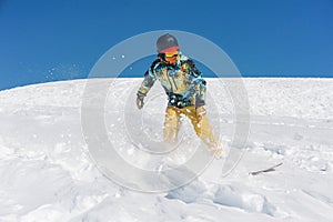 Professional snowboarder in bright sportswear riding down a mountain slope