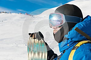 A professional snowboarder stands with his snowboard. Close-up. Portrait of a freerider