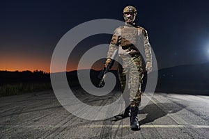 A professional soldier in full military gear striding through the dark night as he embarks on a perilous military