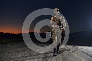 A professional soldier in full military gear striding through the dark night as he embarks on a perilous military