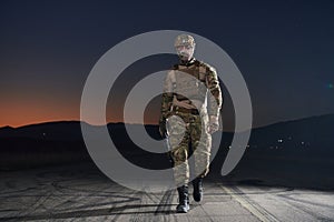 A professional soldier in full military gear striding through the dark night as he embarks on a perilous military