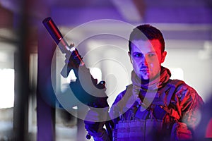 A professional soldier undertakes a perilous mission in an abandoned building illuminated by neon blue and purple lights