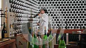 Professional sommelier choosing wine in winery cellar. Specialist taking bottle