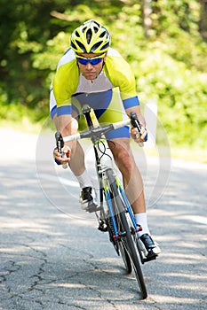 Professional sport Cyclist riding a bike on an open road down the hill on a hot summer day