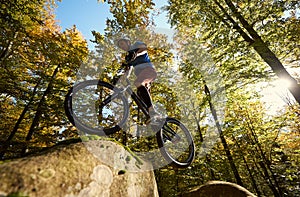 Professional sportsman cyclist jump on trial bike on boulder