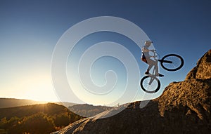 Professional sportsman cyclist jump on trial bike on boulder