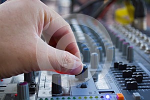 Professional stage sound mixer closeup at sound engineer hand using audio mix slider