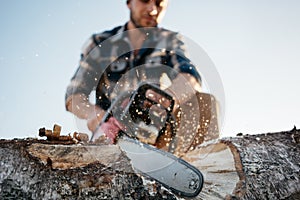 Professional strong lumberman sawing a big tee on sawmill