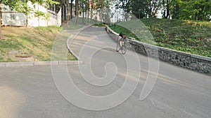 Professional strong skinny cyclist pedaling hard towards hill as a part of his training. Slow motion