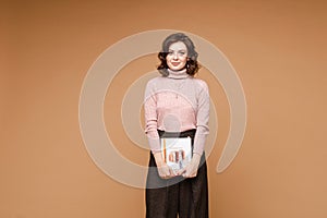 Professional stylist with a book in hands. dark brown trousers holding a book