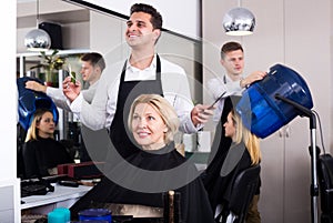 Professional stylist cutting hair of elderly blonde