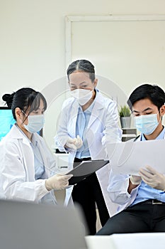 A professional Asian senior female doctor training two Asian junior specialist in the lab photo