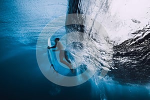 Professional surfer with surfboard dive underwater. Alone surfer under big ocean wave.