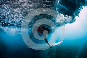 Professional surfer woman with surfboard dive under wave