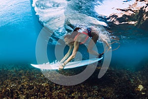 Professional surfer woman with surfboard dive underwater with ocean wave.