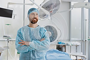 Professional surgeon standing in operating room with crossing hands, ready to work on patient