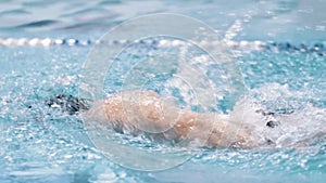 Professional swimmer in goggles floating at swimming pool competition