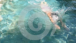 Professional swimmer in pool trains swimming freestyle in clear blue water, wearing swimming goggles. Professional