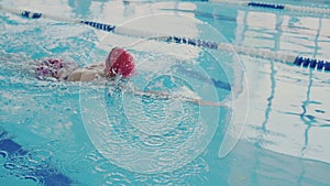 Professional swimmer trains in the pool. She swims like a crawl and skillfully makes a stroke with her hands. Body