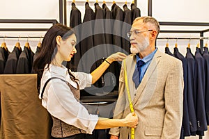 a professional tailor woman trying on a tailor-made suit for an elderly man