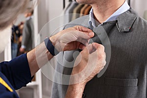 Professional tailor working with client in atelier, closeup