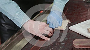 Professional tanner uses a rag to rugs a belt. Working process of the leather belt in the leather workshop.