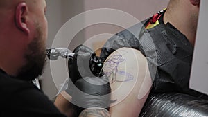 Professional tattoo artist makes a tattoo on a man s arm.