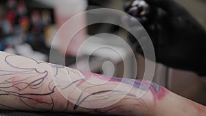 Professional tattoo artist makes a tattoo on a man s arm.