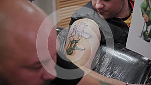 Professional tattoo artist makes a tattoo on a man s arm.