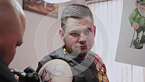 Professional tattoo artist makes a tattoo on a man s arm.