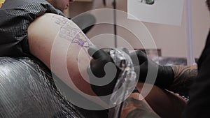 Professional tattoo artist makes a tattoo on a man s arm.